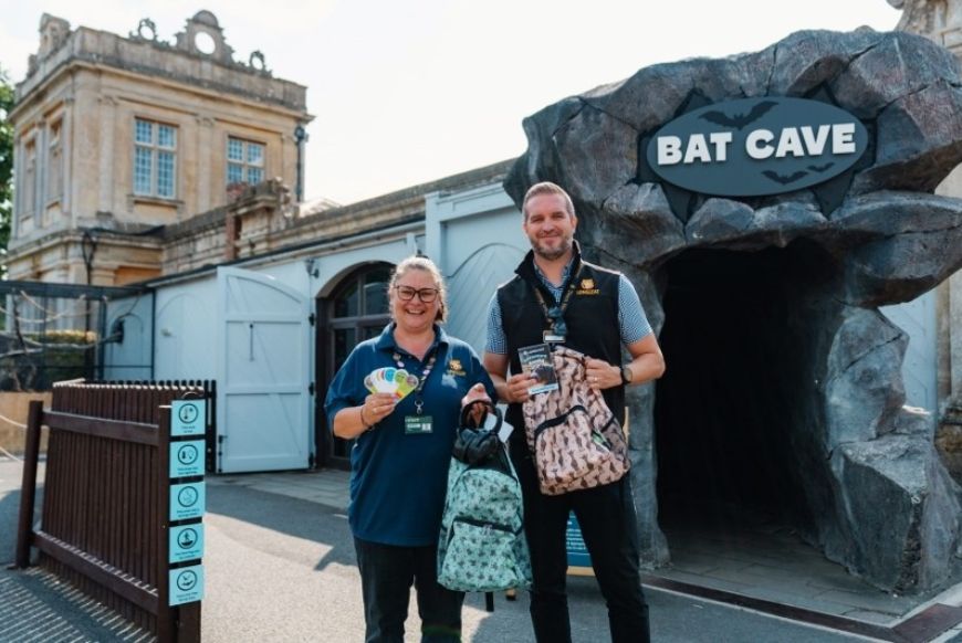 two people standing in front of a building called the bat cave, holding backpacks filled with sensory toys